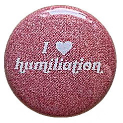 a faded red pin with white text reading 'I heart humiliation'