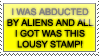 a shiny yellow stamp with black text reading 'I WAS ABDUCTED BY ALIENS AND ALL I GOT WAS THIS LOUSY STAMP'